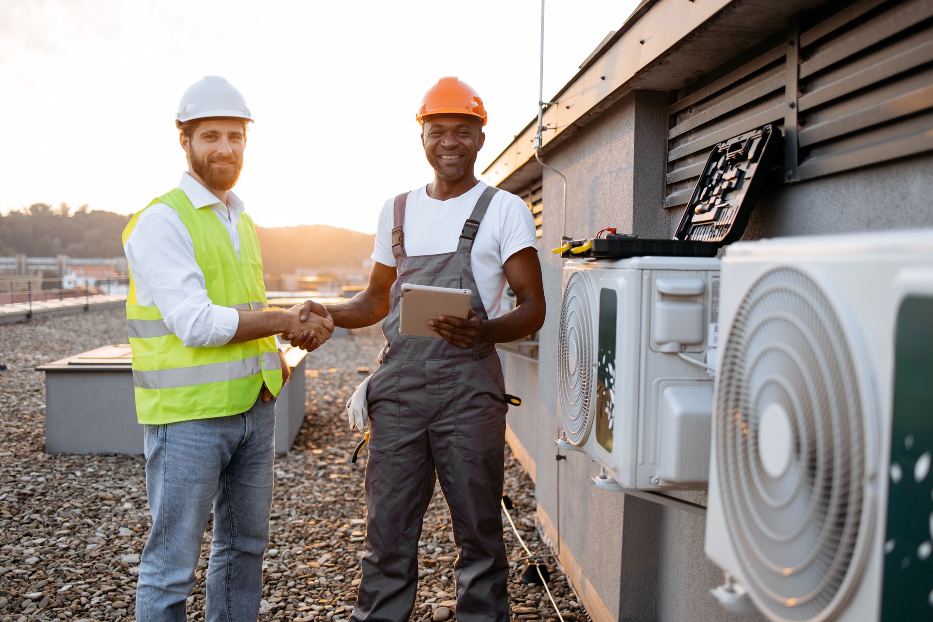 Men shaking hands and standing near air conditioner outdoors